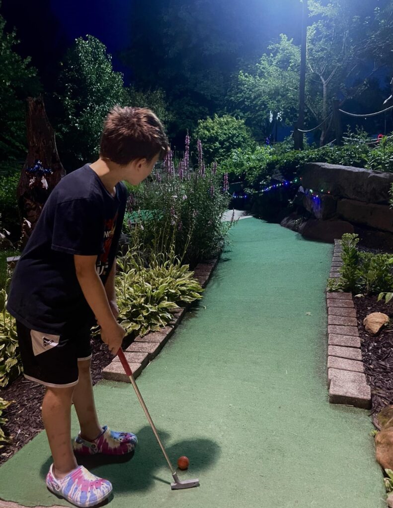 Boy lining up his putt for mini golf at Late Night Golf.